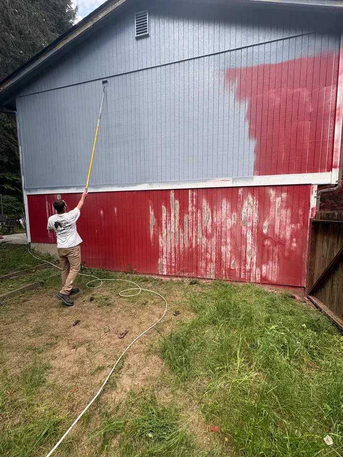 Painter applying primer coat to prepared exterior house siding