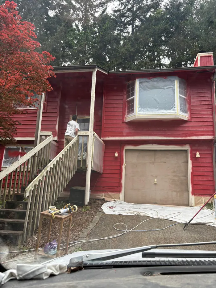 Red exterior siding coat in progress with trim work still underway
