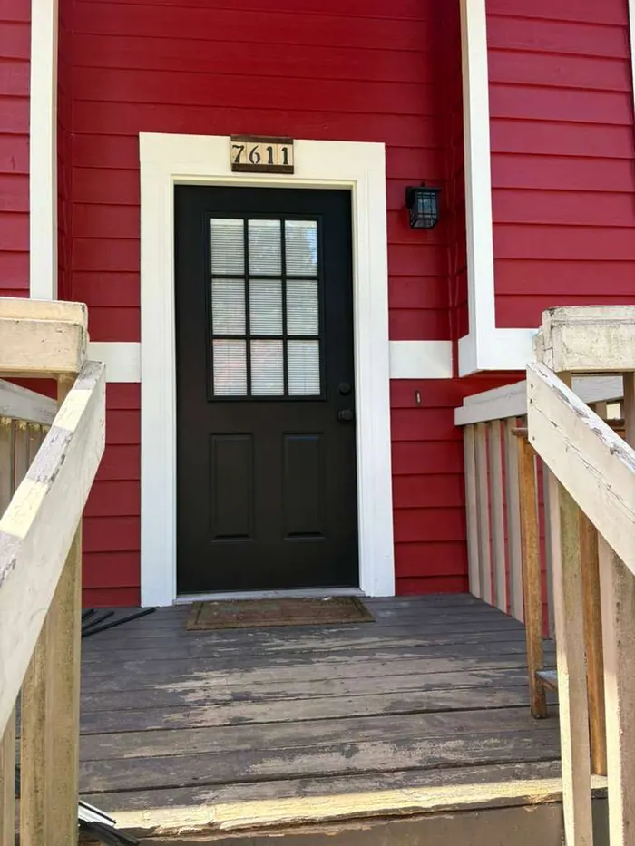 Black front door with freshly painted white trim and red siding